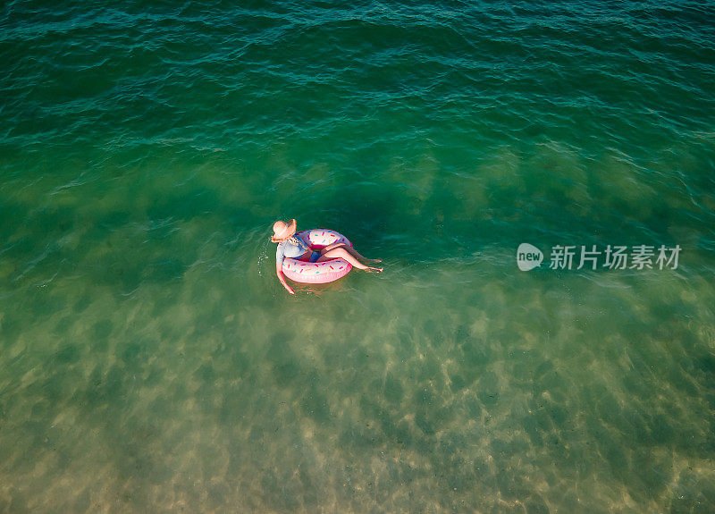 女人游泳和漂浮在海边的水与甜甜圈浮动鸟瞰图