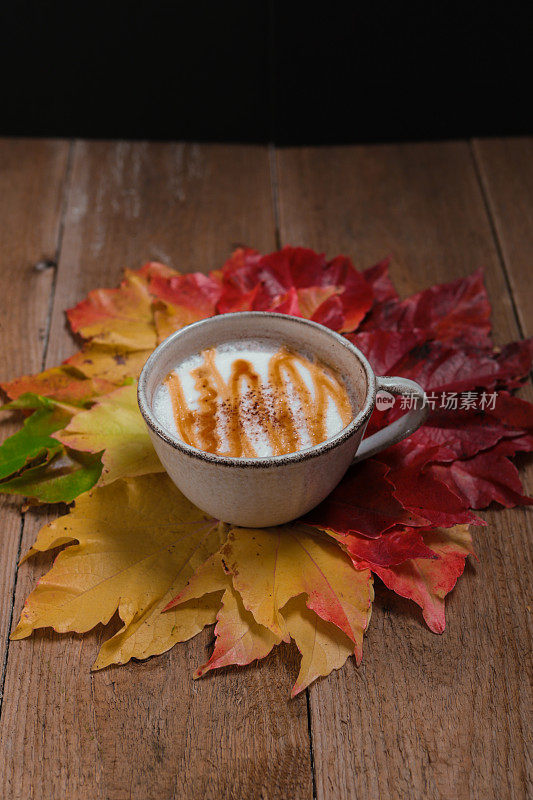 秋天的静物，一杯咖啡和五颜六色的枯叶在木板上