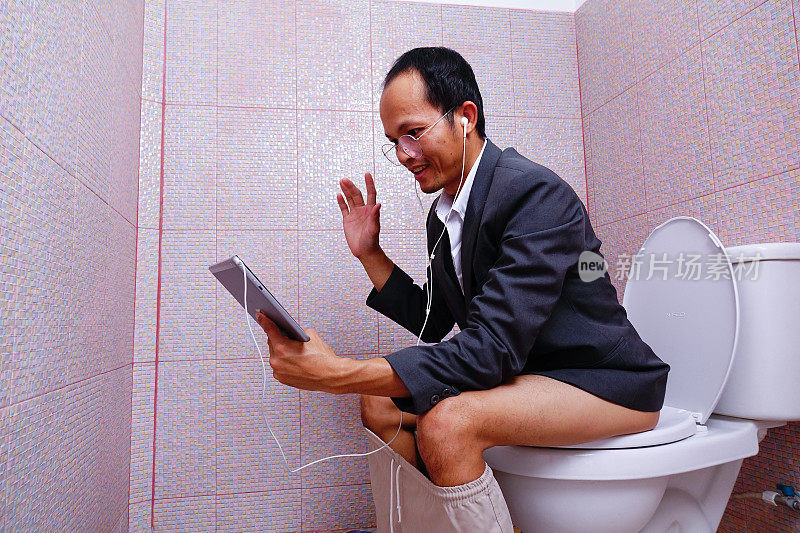 一个男人在厕所用平板电脑开视频会议。呆在家里。