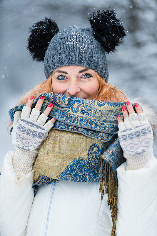 快乐的女人，在冬天森林附近的白雪皑皑的草地上