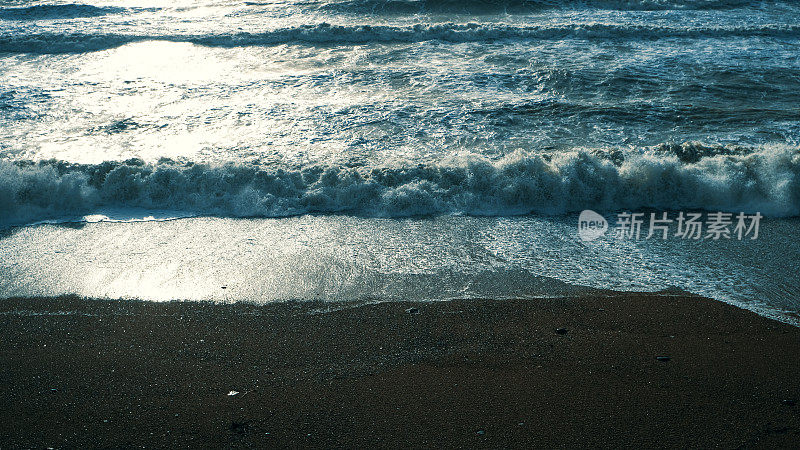 夕阳西下时，海浪翻滚在海滩上