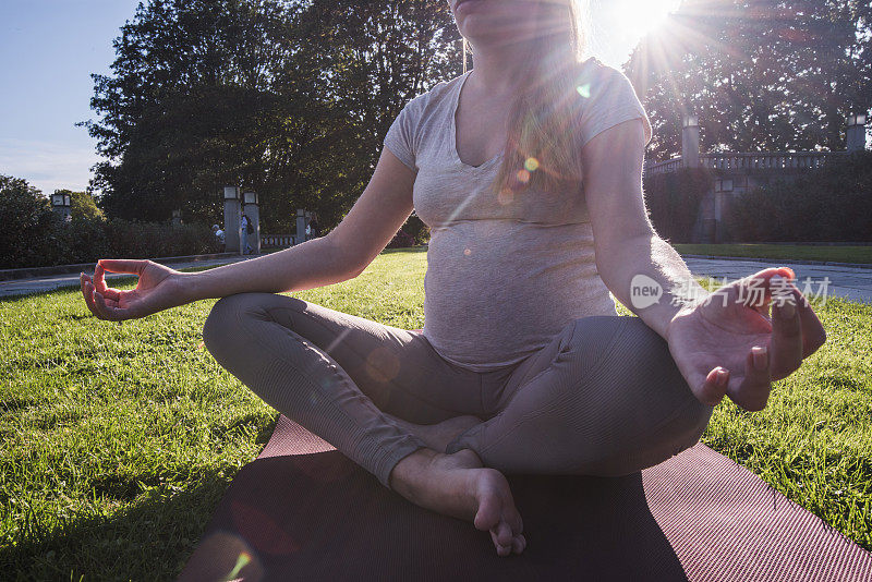陌生孕妇在户外做瑜伽的特写。