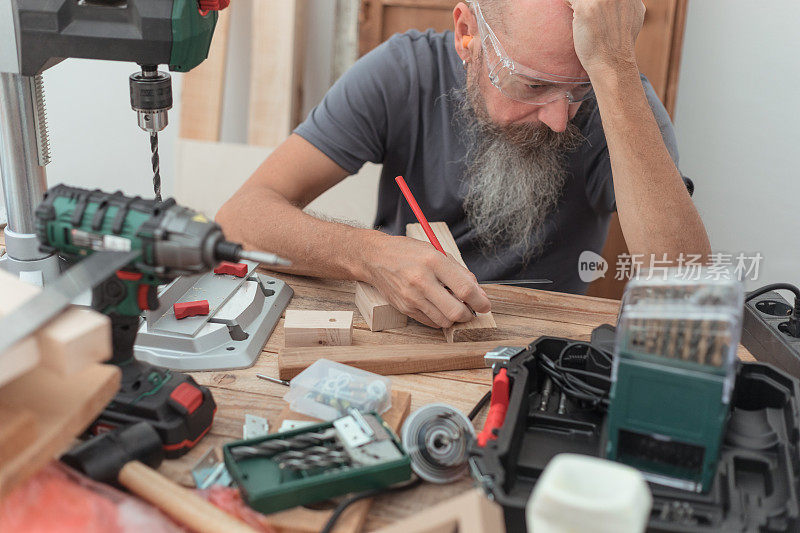 50岁的男人坐在木工车间，思考着项目