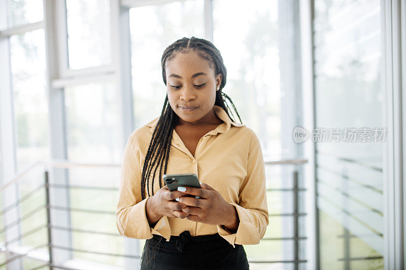 非裔美国女商人使用智能手机发短信的肖像