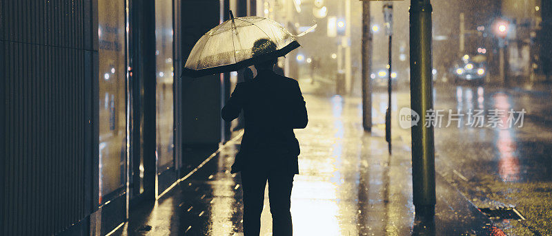 带着雨伞独自在雨中行走的人。城市街道-空无一人