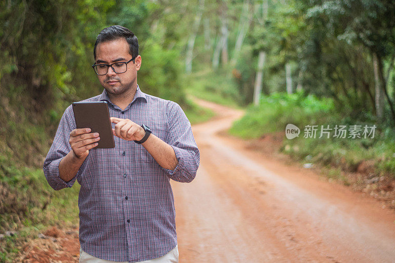 在农村地区，年轻的企业家正在检查他的平板电脑