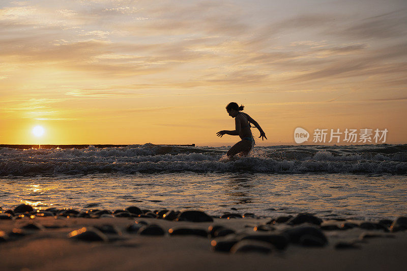 日落时分，小女孩在波罗的海的波涛中奔跑