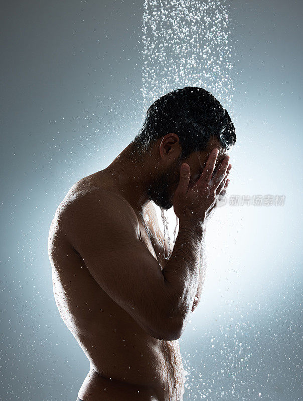 工作室拍摄了一个年轻人在淋浴中洗头发，背景是灰色的