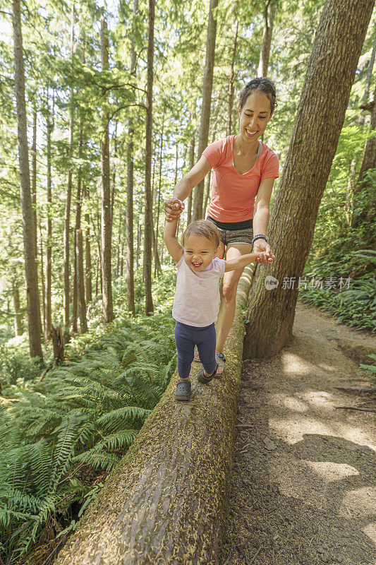 快乐的妈妈和蹒跚学步的孩子在森林里愉快的徒步旅行