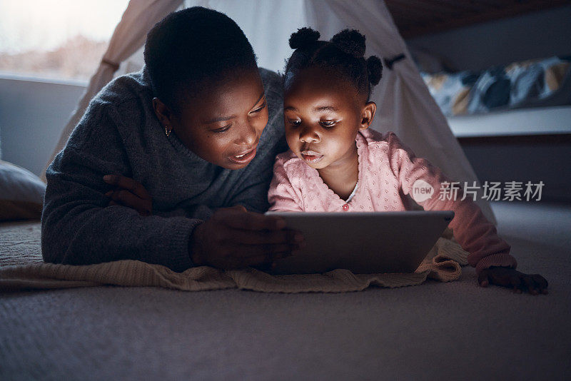 一位母亲和她的女儿在电子平板电脑上读睡前故事