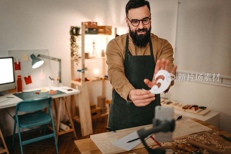 男性工匠展示纸，而视频在艺术工作室