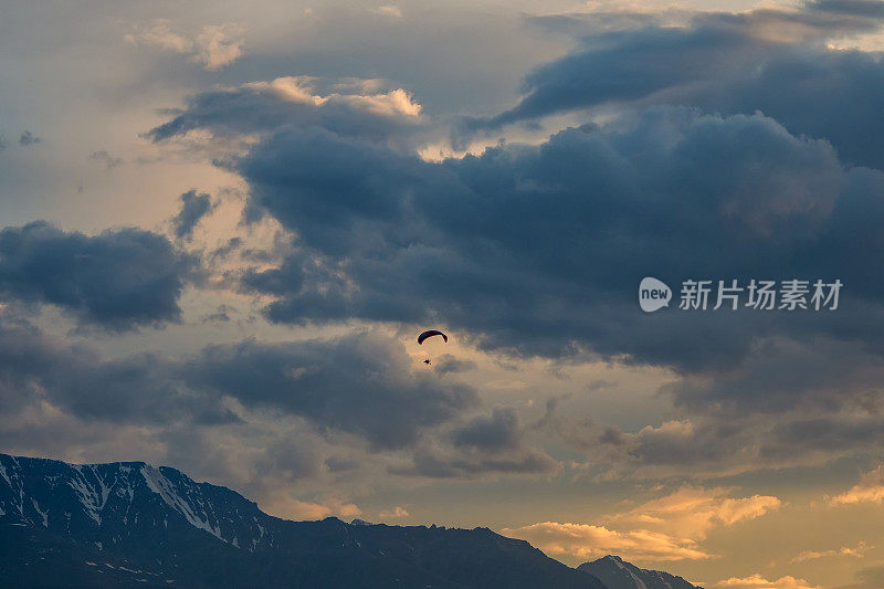 彩色滑翔伞在多云的夜空下滑行。滑翔伞，极限运动的概念。滑翔伞，日落时飞翼。