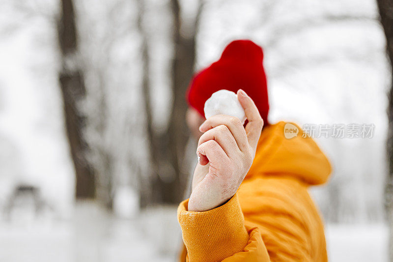 年轻英俊的男子在冬天的一天里，穿着暖和的衣服扔雪球