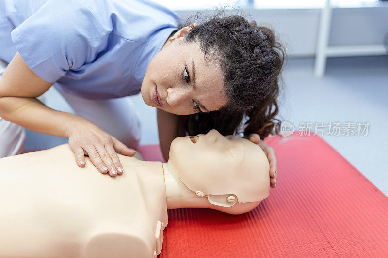 在急救训练中，一名妇女在假人身上练习心肺复苏术。急救训练-心肺复苏。假人心肺复苏急救课程。