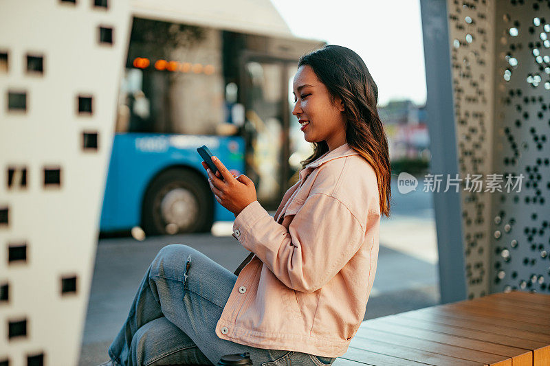 女人在等车，坐在公交车站，打电话