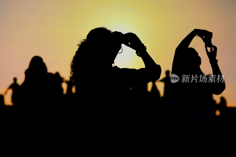 人们在夕阳的背景下拍照的剪影
