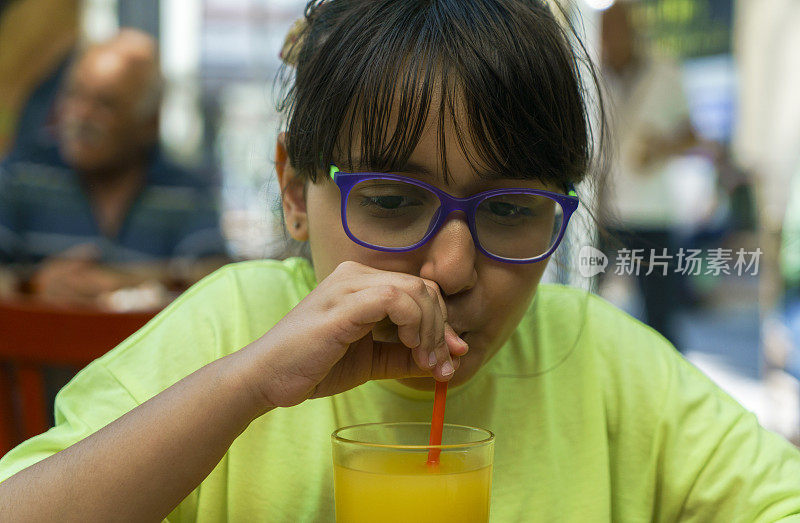一个美丽的女孩喝着新鲜的果汁