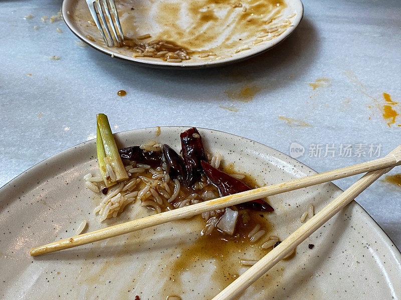 中国外卖餐残留在脏盘子上的特写图像，餐具，金属叉子，一次性木筷子，重点放在前景