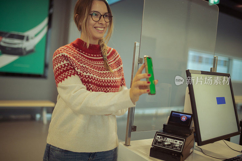 可爱的女人用手机应用程序在机场办理登机手续