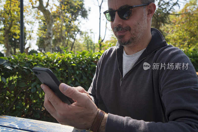 一名男子坐在室外路边咖啡馆使用智能手机
