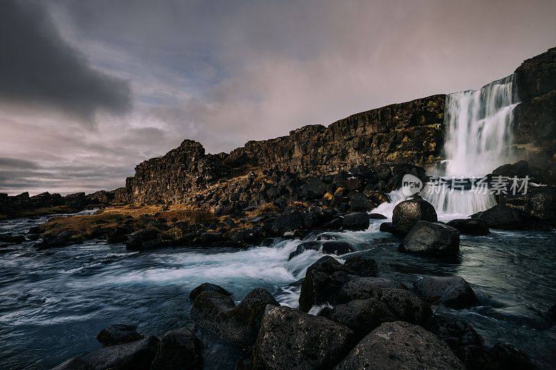 冰岛美丽的风景，在多云的天气下，瀑布顶着岩石峭壁
