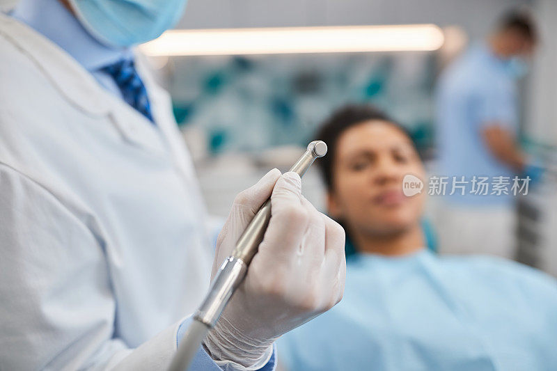 近距离的牙医使用牙钻与病人在牙科诊所工作。