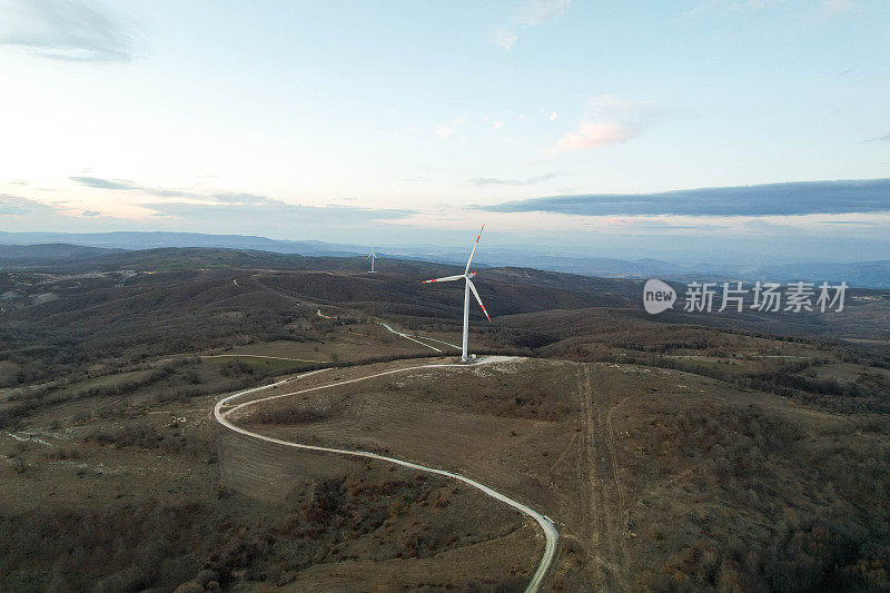 日落时的太阳能电池板和风力涡轮机。可再生能源