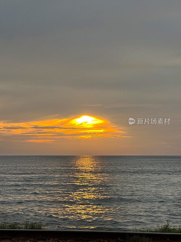 海上日落天空特写，空海岸线(南线)铁路线平行于海岸线，金属铁轨和砾石，斯里兰卡科伦坡，重点在前景