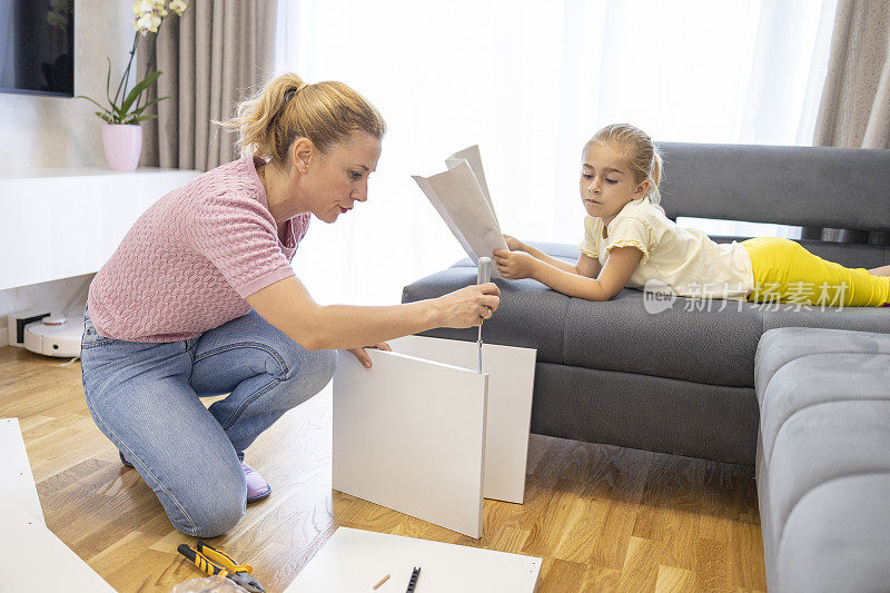 孩子在休息，看着妈妈组装家具