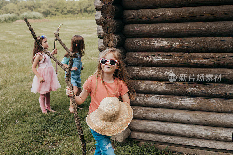 小学的小女孩们在夏令营的小屋外徒步旅行时拿着拐杖