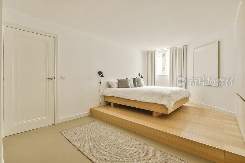 一间卧室，有一张木制的台床和白色的墙壁