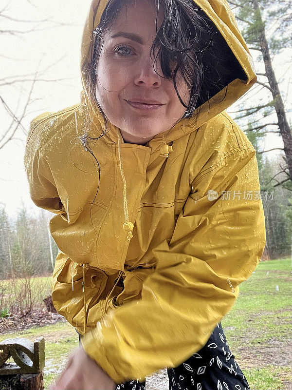 穿着黄色雨衣在户外享受春雨的女人。