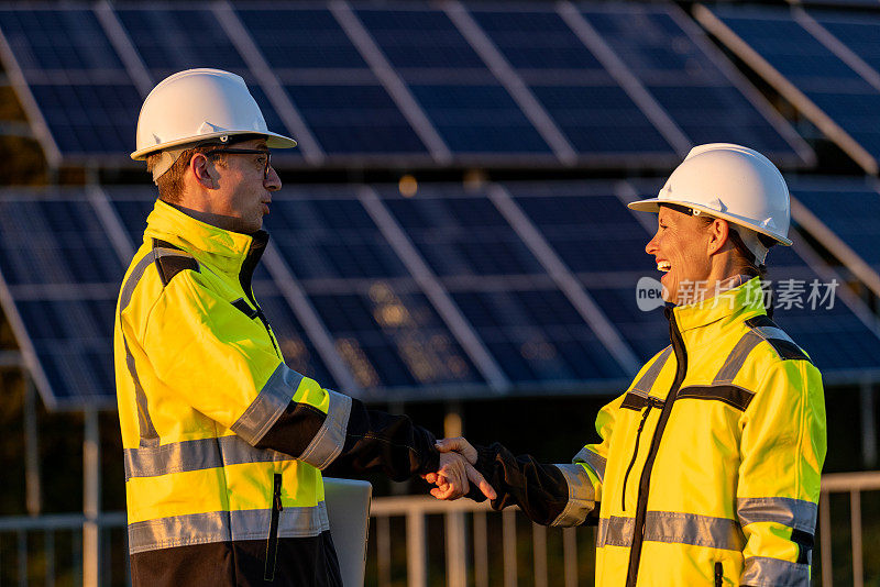 两名工程师在太阳能电站里穿着反光服握手