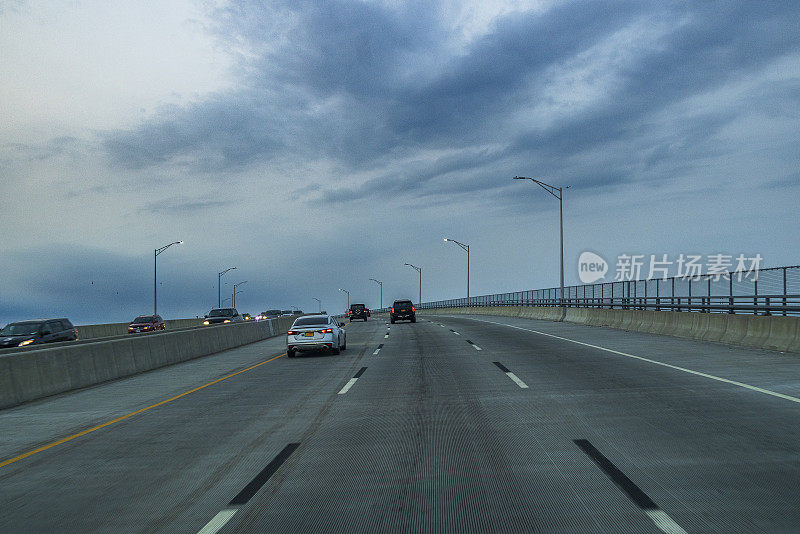 空旷的高速公路上多云的天空。纽约，布鲁克林，从汽车上看到的标志线和路灯。