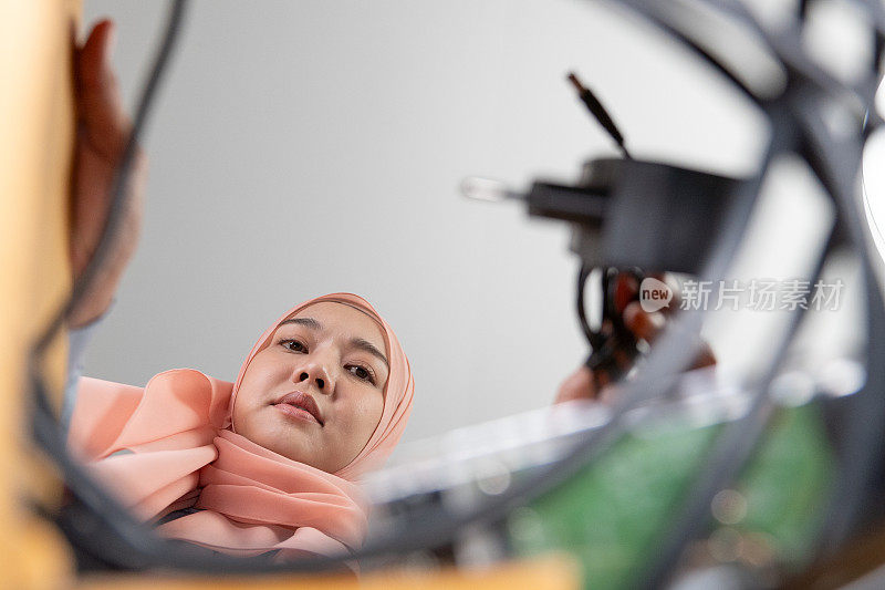 电子废物管理。美丽的亚洲穆斯林妇女把电子垃圾放在纸板箱里，送去回收或妥善处理。环境可持续性。电子垃圾。