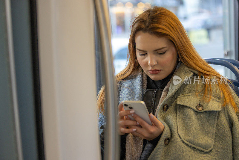 年轻女子在电车上使用手机。