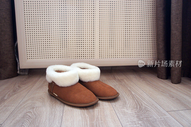 白色毛皮的棕色雪地靴。家里拖鞋旁边的房间里放着电池。