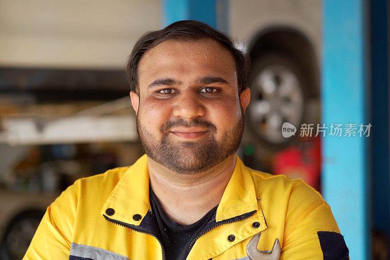 图为亚洲男性汽车技师在车库里摆姿势拍照。