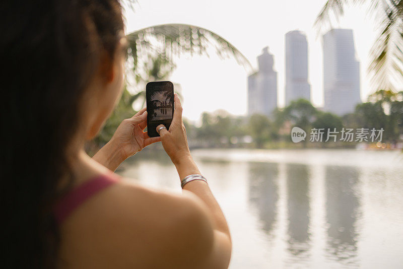 一个女运动员在湖边用手机拍照的特写。