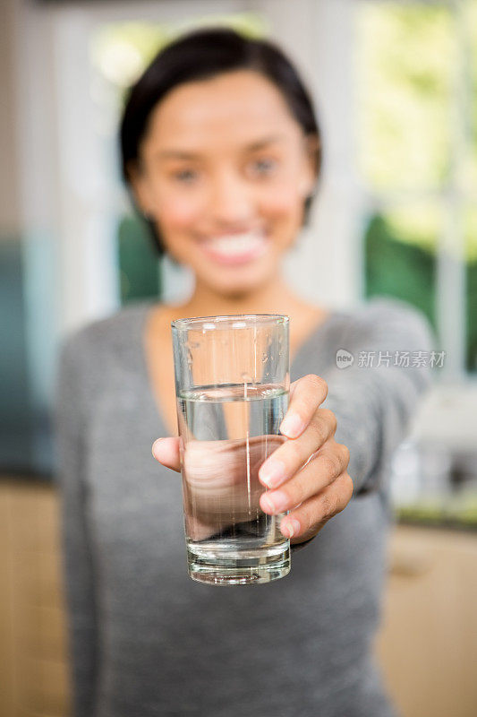 微笑的黑发女子拿着一杯水