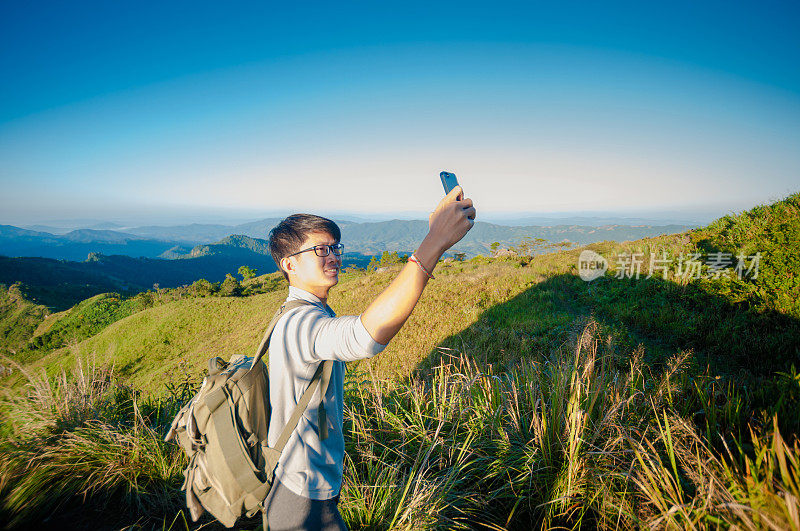 年轻的旅行者站在山上望着夕阳。