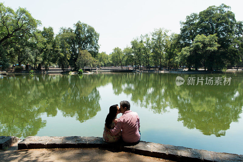 一对成熟的情侣坐在湖边亲吻
