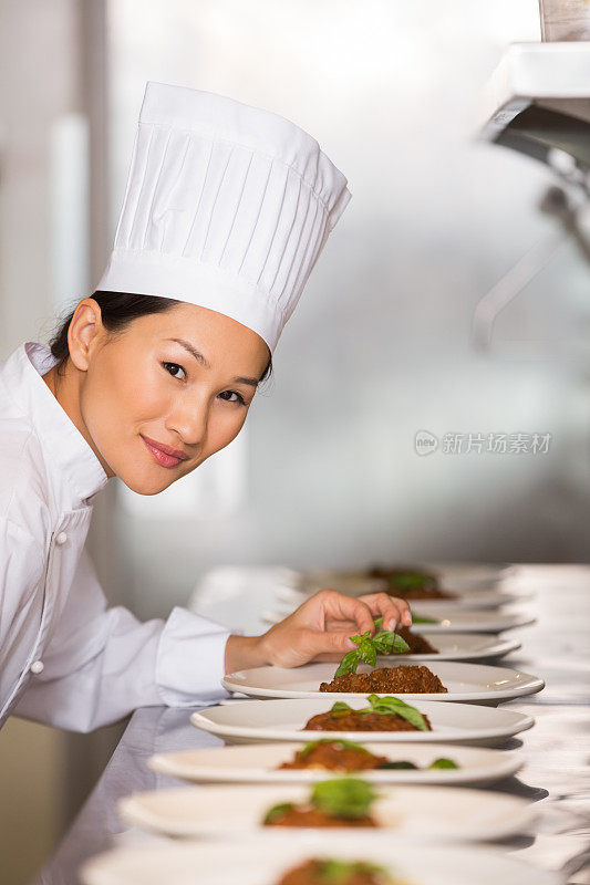 微笑的女厨师在厨房装饰食物
