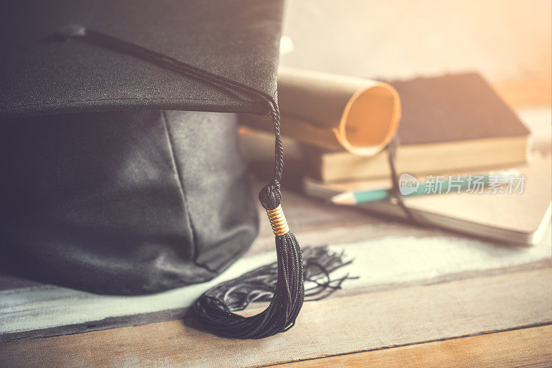毕业帽，带学位帽的木桌上有毕业概念。