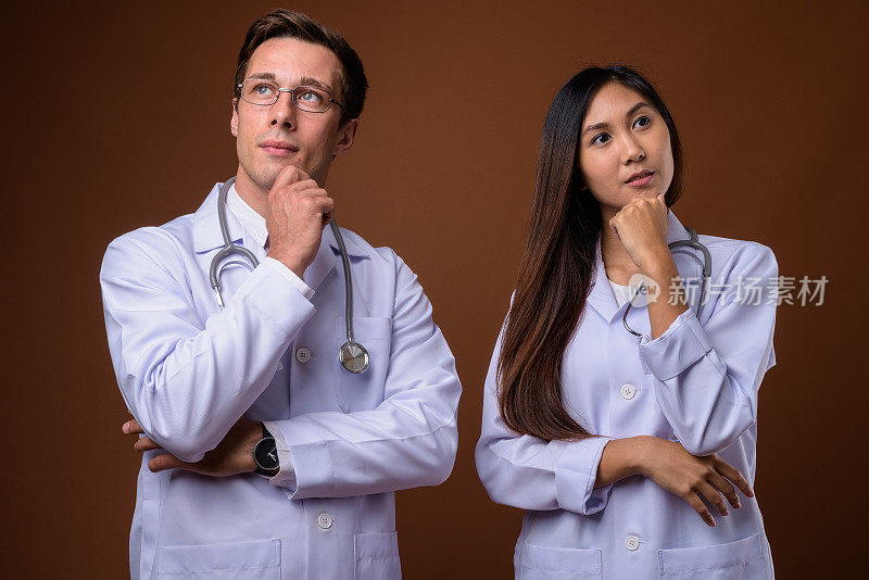 工作室拍摄的年轻英俊的男子医生和年轻美丽的亚洲女医生一起对彩色的背景