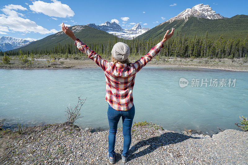 年轻女子的双臂伸向山湖