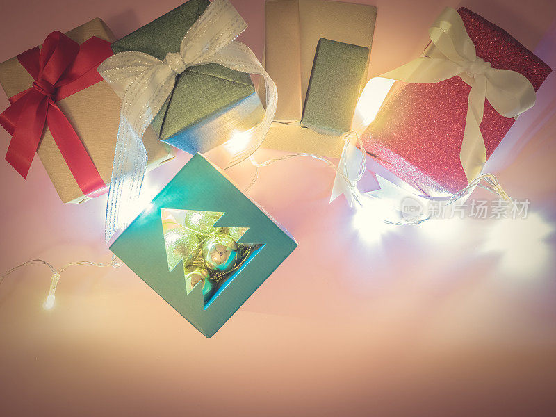 欢迎和庆祝圣诞节，生日或新年的一组包装礼物盒，圣诞树纸和装饰灯在粉红色的背景