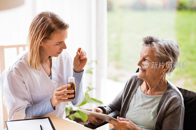 健康访视员和一位服用药片的老年妇女。