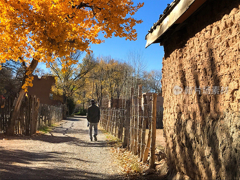 圣塔菲，内省:在土坯墙的秋天小路上行走的人