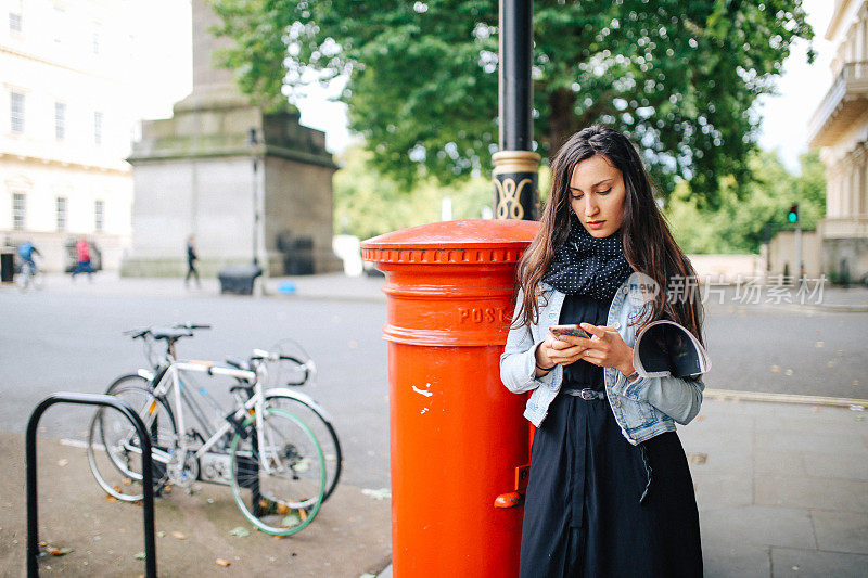 一名年轻女子在英国伦敦街头用手机发短信